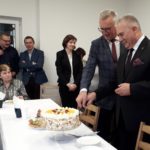 Na zdjęciu dwóch mężczyzn kroi wspólnie tort z okazji otwarcia klubu seniora w Poświętnem